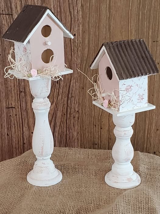 two pink and white birdhouses mounted on painted candlesticks