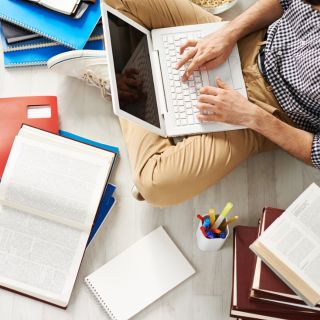 Laptop and books on a desk for online research